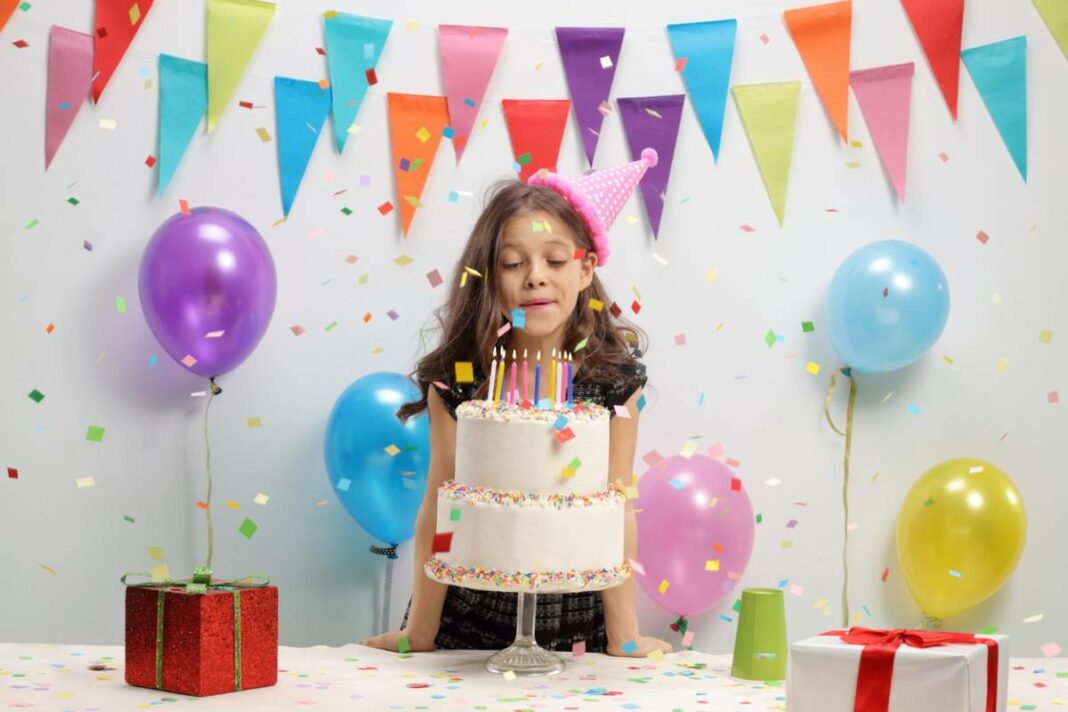 petite fille qui souffle les bougies de son gâteau d'anniversaire