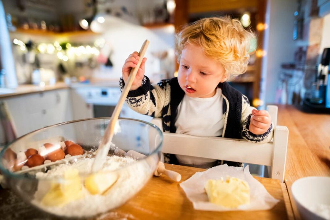 enfant qui fait un gâteau depuis sa tour d'observation Montessori